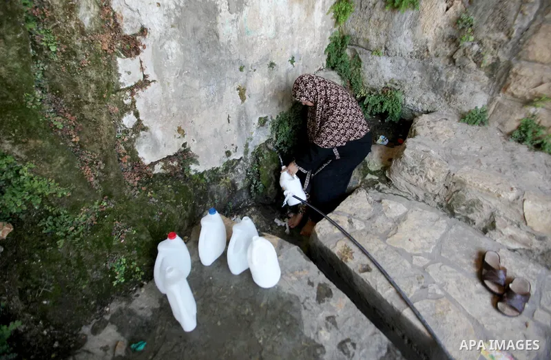 A Palestinian woman fills a jerrican with spring water on June 27, 2016 in Salfit, north of Ramallah, where some of the West Bank village's inhabitants have been without water for days. Tens of thousands of Palestinians...
