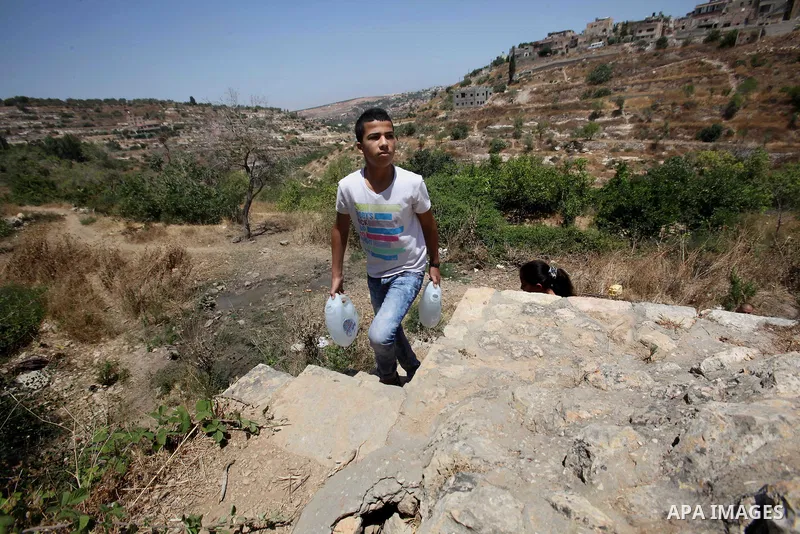 A Palestinian boy carries a jerrican filled with spring water on June 27, 2016 in Salfit, north of Ramallah, where some of the West Bank village's inhabitants have been without water for days. Tens of thousands of Palest...