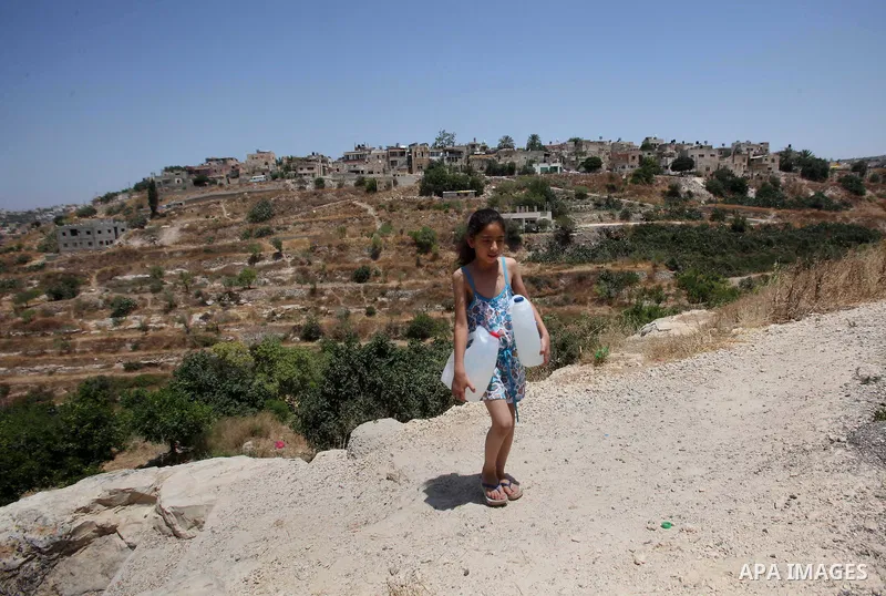 A Palestinian girl carries a jerrican filled with spring water on June 27, 2016 in Salfit, north of Ramallah, where some of the West Bank village's inhabitants have been without water for days. Tens of thousands of Pales...