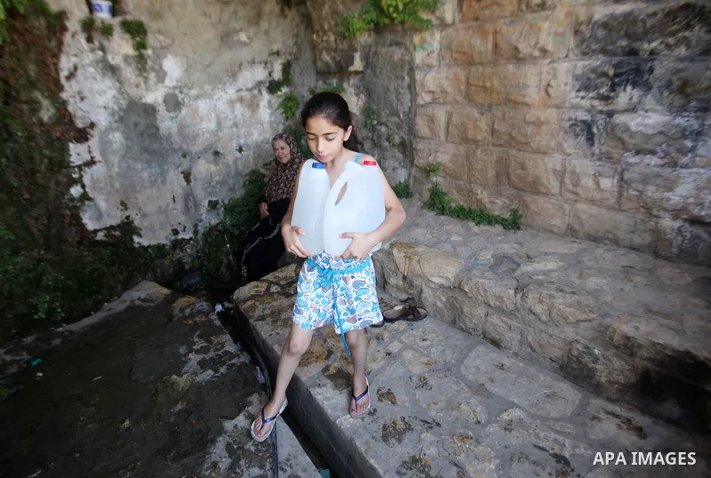 A Palestinian girl carries a jerrican filled with spring water on June 27, 2016 in Salfit, north of Ramallah, where some of the West Bank village's inhabitants have been without water for days. Tens of thousands of Pales...