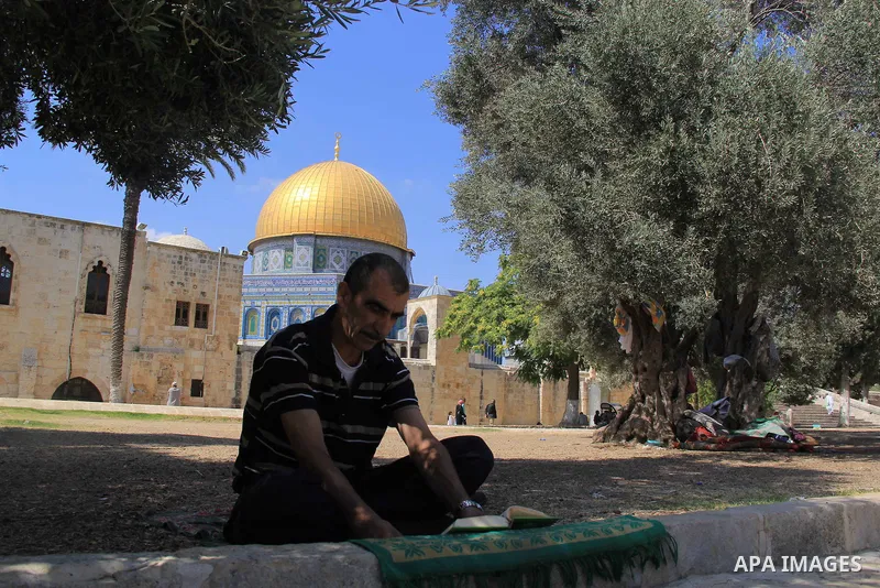 A Palestinian man reads the Koran, Islam's holy book, during the holy month of Ramadan, in front of the Dome of the Rock mosque at the al-Aqsa mosque compound, in Jerusalem's old city, on June 28, 2016. An Israeli police...