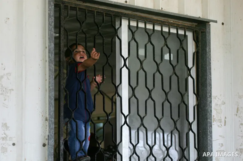 A boy looks out of a window as he waits with his family for a travel permit to cross into Egypt through the Rafah border crossing after it was opened by Egyptian authorities for five days, in the southern Gaza Strip June...