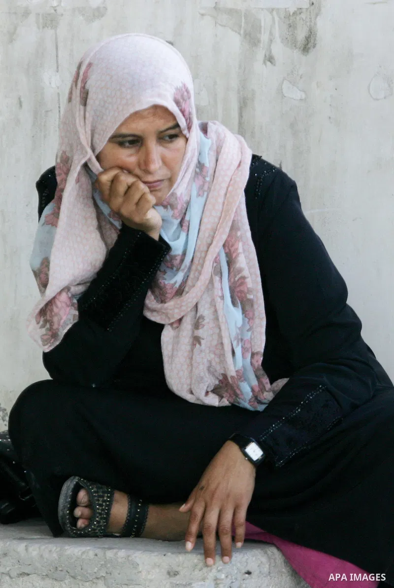 A Palestinian woman waits for a travel permit to cross into Egypt through the Rafah border crossing after it was opened by Egyptian authorities for five days, in the southern Gaza Strip June 29, 2016. Photo by Abed Rahim...