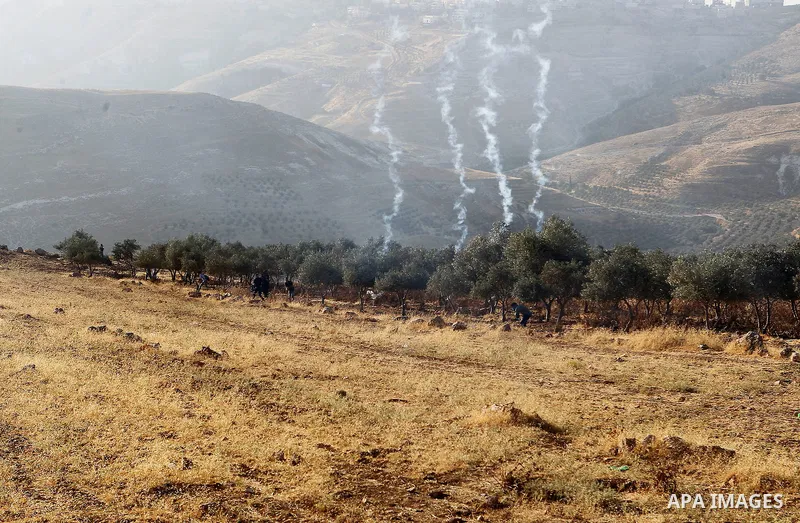 Palestinians run for a cover from teargas canisters fired by Israeli border police near a barbed-wire gate part of the controversial Israeli separation fence between the West Bank town of Bethlehem and Jerusalem, after a...