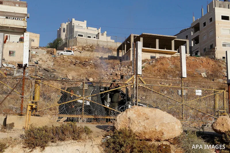 Palestinian men cross through a gap in the barbed-wire gate part of the controversial Israeli separation fence between the West Bank town of Bethlehem and Jerusalem, in an attempt to reach the Al-Aqsa Mosque compound in...