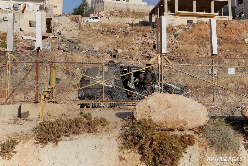 Palestinians run for a cover from teargas canisters fired by Israeli border police near a barbed-wire gate part of the controversial Israeli separation fence between the West Bank town of Bethlehem and Jerusalem, after a...