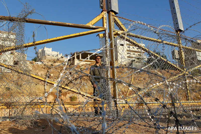 An Israeli border policeman stands guard near a gap in the barbed-wire gate part of the controversial Israeli separation fence between the West Bank town of Bethlehem and Jerusalem, after an attempt by Palestinian men to...