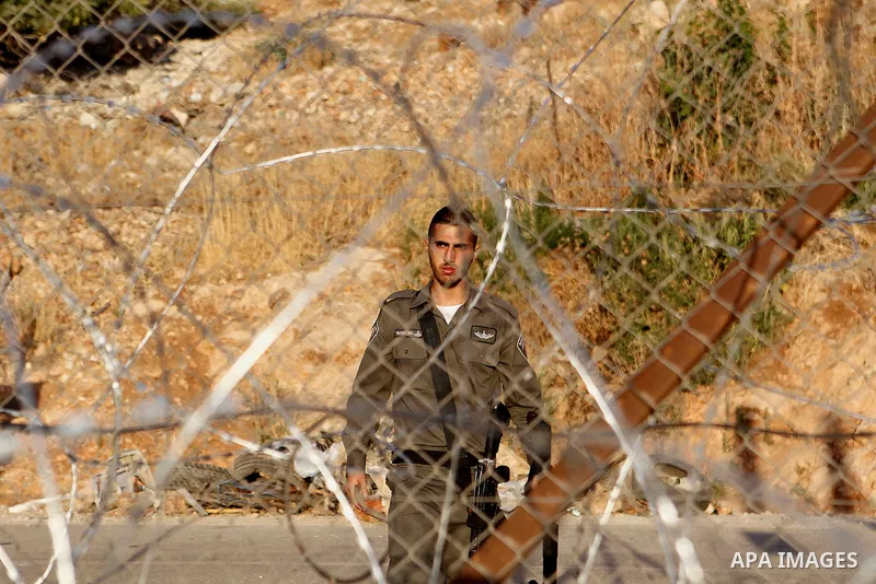 An Israeli border policeman stands guard near a gap in the barbed-wire gate part of the controversial Israeli separation fence between the West Bank town of Bethlehem and Jerusalem, after an attempt by Palestinian men to...
