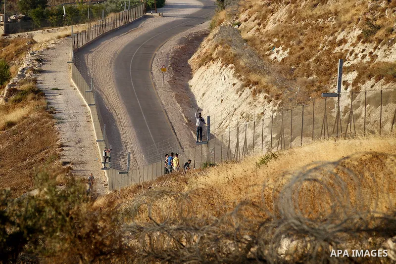 Palestinian men cross through a gap in the barbed-wire gate part of the controversial Israeli separation fence between the West Bank town of Bethlehem and Jerusalem, in an attempt to reach the Al-Aqsa Mosque compound in...