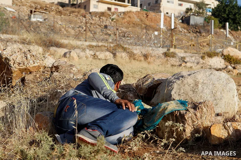 Palestinians run for a cover from teargas canisters fired by Israeli border police near a barbed-wire gate part of the controversial Israeli separation fence between the West Bank town of Bethlehem and Jerusalem, after a...