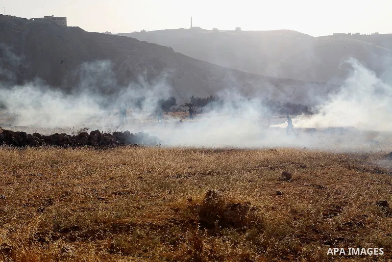 Palestinians run for a cover from teargas canisters fired by Israeli border police near a barbed-wire gate part of the controversial Israeli separation fence between the West Bank town of Bethlehem and Jerusalem, after a...