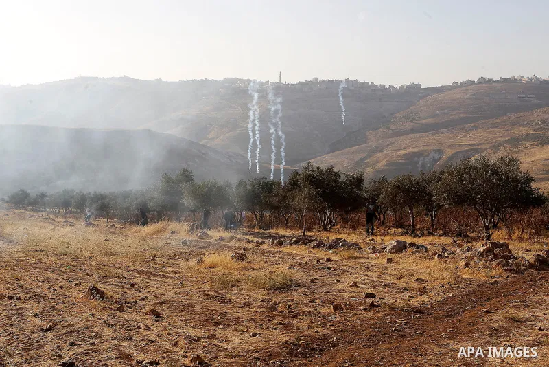 Palestinians run for a cover from teargas canisters fired by Israeli border police near a barbed-wire gate part of the controversial Israeli separation fence between the West Bank town of Bethlehem and Jerusalem, after a...