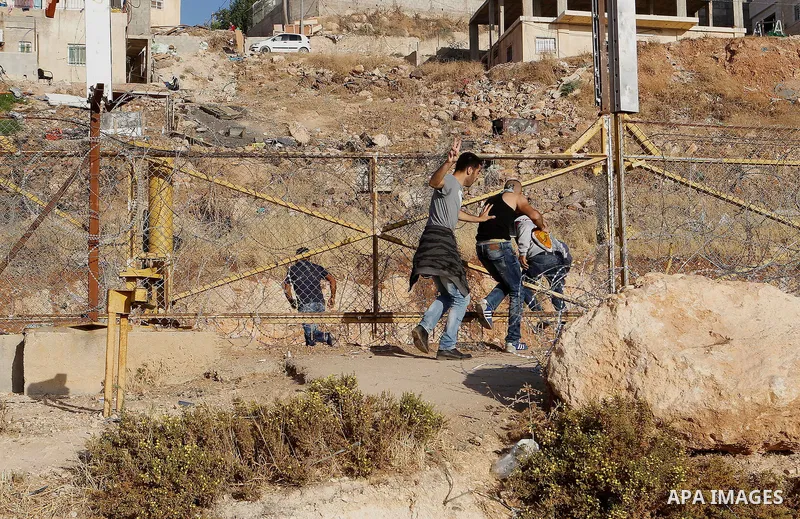 Palestinian men cross through a gap in the barbed-wire gate part of the controversial Israeli separation fence between the West Bank town of Bethlehem and Jerusalem, in an attempt to reach the Al-Aqsa Mosque compound in...