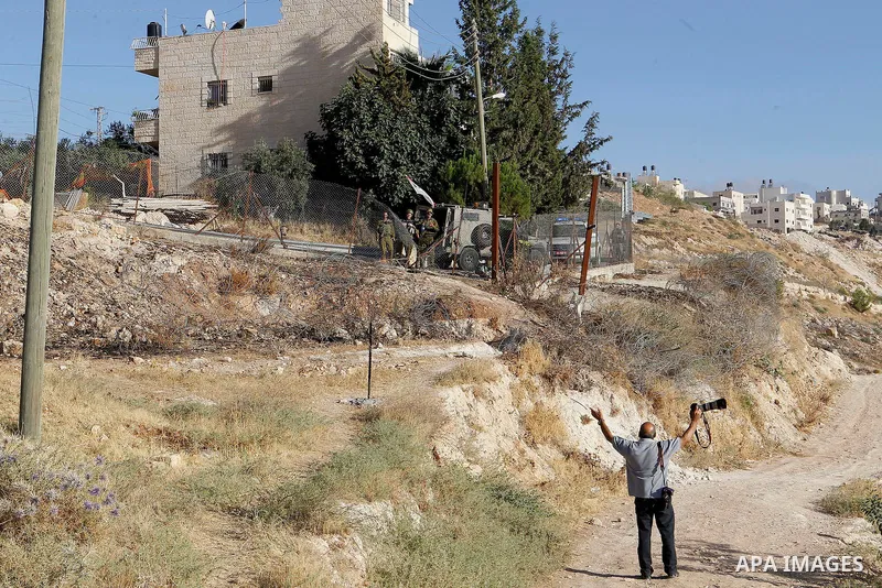 A Palestinian photographer reacts as Israeli border police fire teargas canisters near a barbed-wire gate part of the controversial Israeli separation fence between the West Bank town of Bethlehem and Jerusalem, after an...
