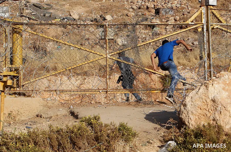 Palestinian men cross through a gap in the barbed-wire gate part of the controversial Israeli separation fence between the West Bank town of Bethlehem and Jerusalem, in an attempt to reach the Al-Aqsa Mosque compound in...