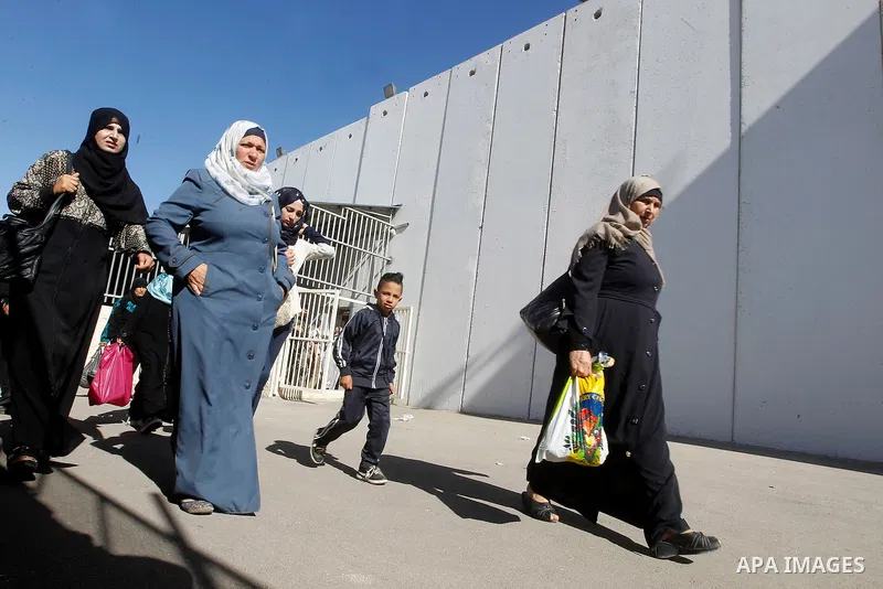 Palestinian women cross an Israeli checkpoint between the West Bank town of Bethlehem and Jerusalem, as they head to Jerusalem's Al-Aqsa Mosque compound on the forth and last Friday of the Muslim holy month of Ramadan on...