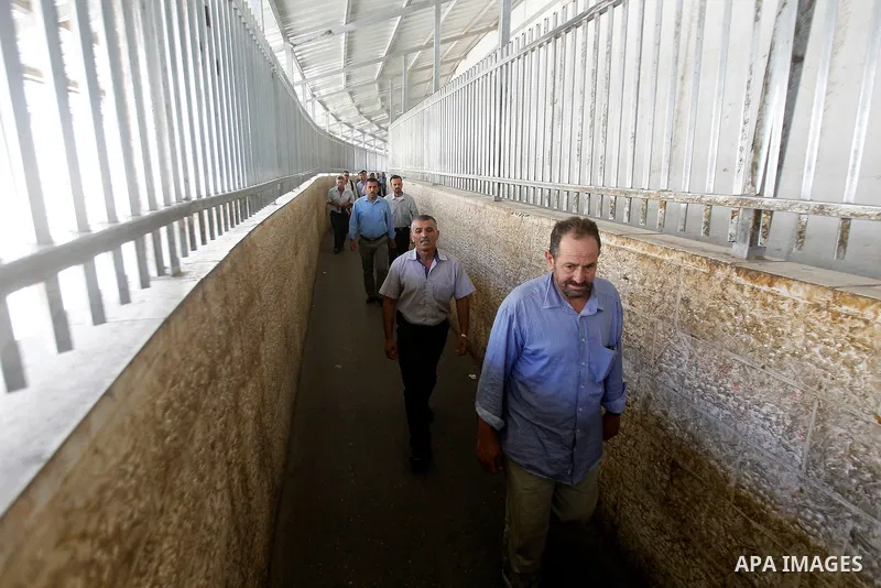 Palestinian men cross an Israeli checkpoint between the West Bank town of Bethlehem and Jerusalem, as they head to Jerusalem's Al-Aqsa Mosque compound on the forth and last Friday of the Muslim holy month of Ramadan on J...