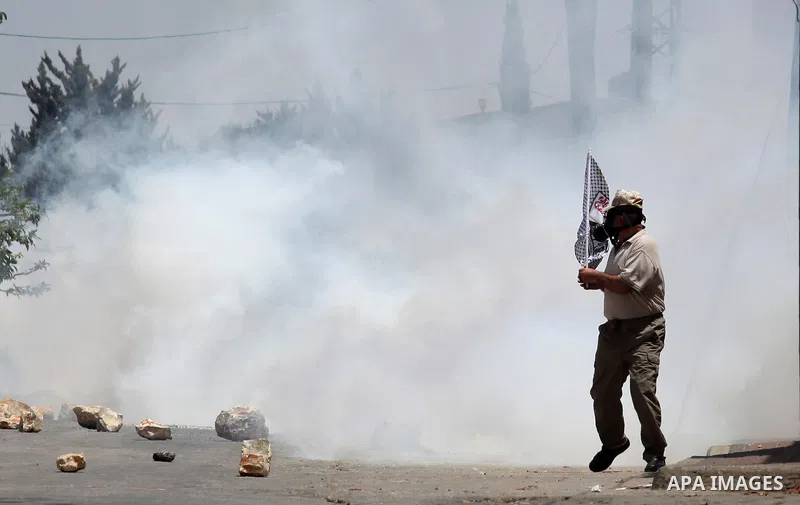 A Palestinian protester runs for cover from a tear gas fired by Israeli security forces during clashes following a demonstration against the expropriation of Palestinian land by Israel on July 01, 2016 in the village of...