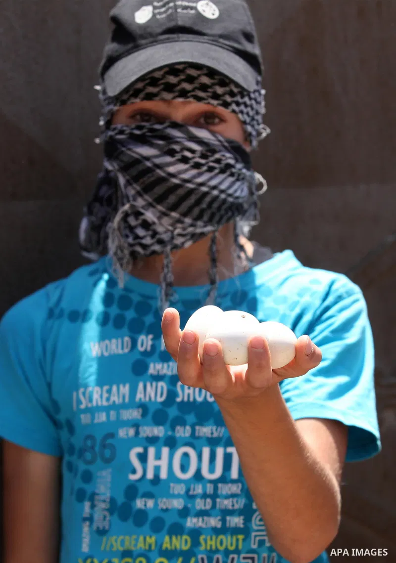 A Palestinian protester carries eggs during clashes with Israeli security forces following a demonstration against the expropriation of Palestinian land by Israel on July 01, 2016 in the village of Kfar Qaddum, near Nabl...