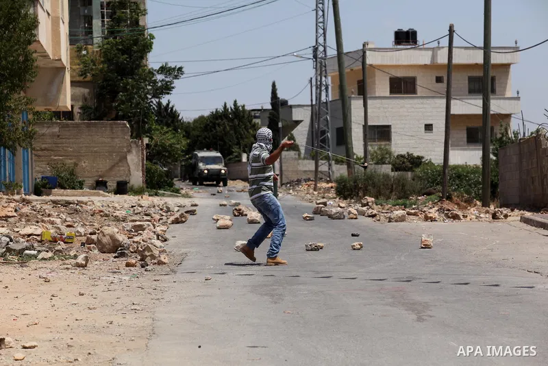 A Palestinian protester uses a slingshot to hurl stones towards Israeli security forces during clashes following a demonstration against the expropriation of Palestinian land by Israel on July 01, 2016 in the village of...