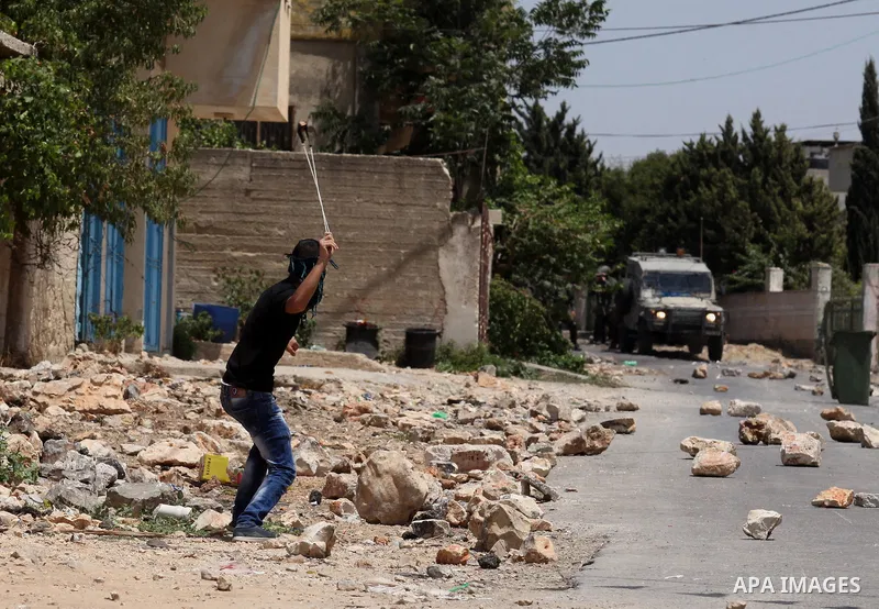 A Palestinian protester uses a slingshot to hurl stones towards Israeli security forces during clashes following a demonstration against the expropriation of Palestinian land by Israel on July 01, 2016 in the village of...