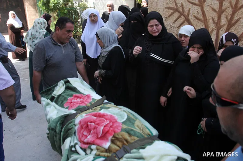 Mourners stand next to the body of Sondos al-Basha, a Palestinian woman who was killed in the Istanbul airport attack blamed on the Islamic State (IS) group on June 28, during her funeral in the West Bank town of Qalqily...