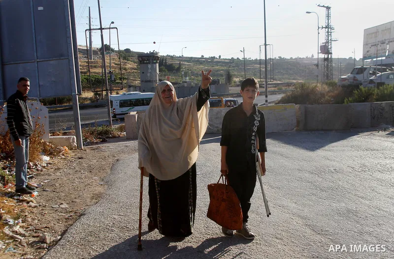 Palestinians walk past a barrier blocking the road in the village of Halhul north of the Israeli occupied West Bank city of Hebron, July 2, 2016. The entire city of Hebron was placed under a general closure, while transf...