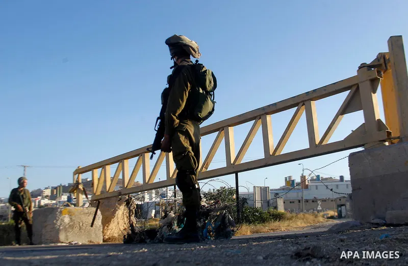 Israeli soldiers close a barrier blocking the road at a southern entrance of Hebron on July 2, 2016, after Israeli troops locked down the occupied West Bank city following Palestinian attacks. Israeli forces locked gates...