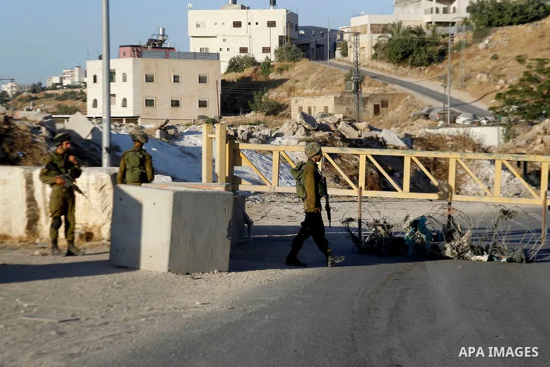 Israeli soldiers close a barrier blocking the road at a southern entrance of Hebron on July 2, 2016, after Israeli troops locked down the occupied West Bank city following Palestinian attacks. Israeli forces locked gates...