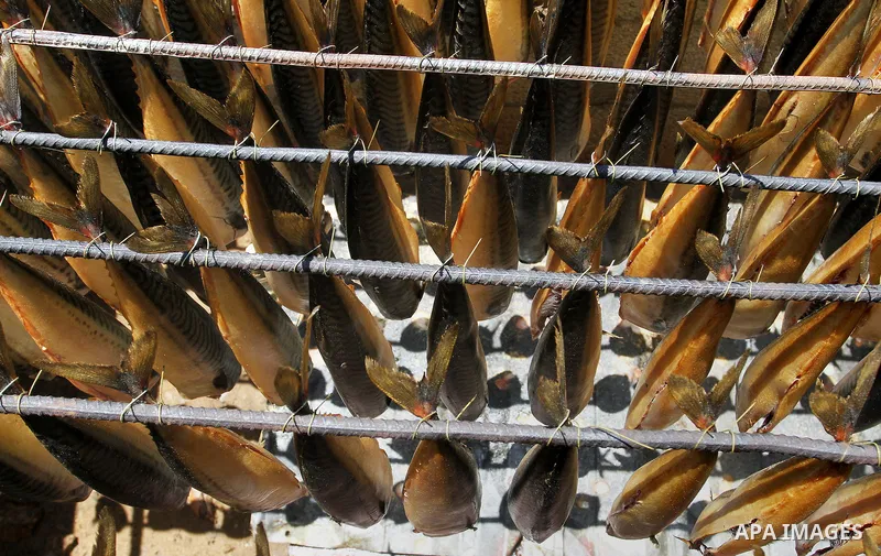 Mackerels are being smoked by Palestinians before selling them at a market ahead of the Eid al-Fitr holiday on July 2, 2016 in Khan Yunis, in the southern Gaza Strip. Eid al-Fitr marks the end of Muslim's holy fasting mo...
