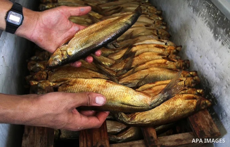 A Palestinian man prepares mackerels to be smoked and sold at a market ahead of the Eid al-Fitr holiday on July 2, 2016 in Khan Yunis, in the southern Gaza Strip. Eid al-Fitr marks the end of Muslim's holy fasting month...