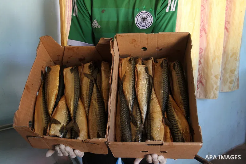 A Palestinian man prepares mackerels to be smoked and sold at a market ahead of the Eid al-Fitr holiday on July 2, 2016 in Khan Yunis, in the southern Gaza Strip. Eid al-Fitr marks the end of Muslim's holy fasting month...
