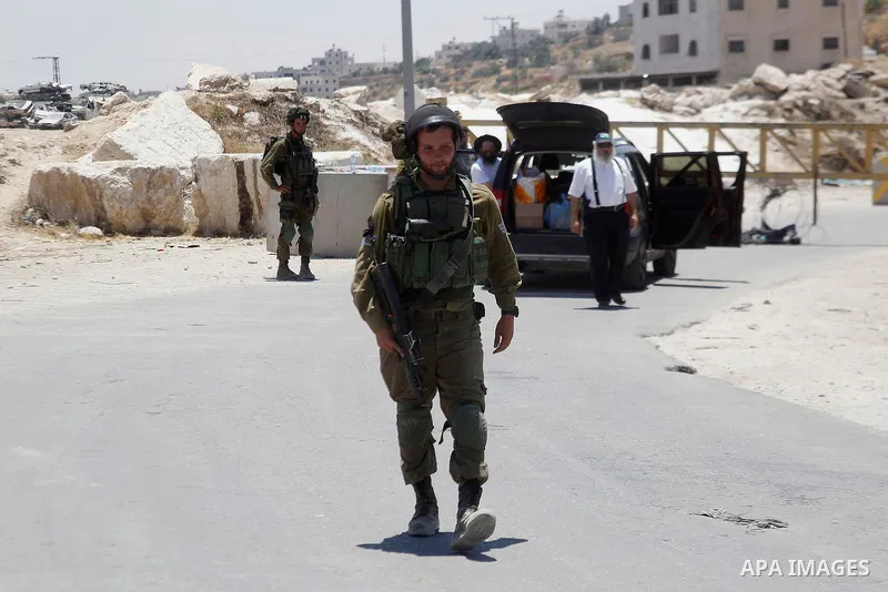 Israeli soldiers close a barrier blocking the road at a southern entrance of Hebron on July 3, 2016, as the army keeps the town under lockdown following clashes and attacks that killed two Israelis. Israeli troops locked...