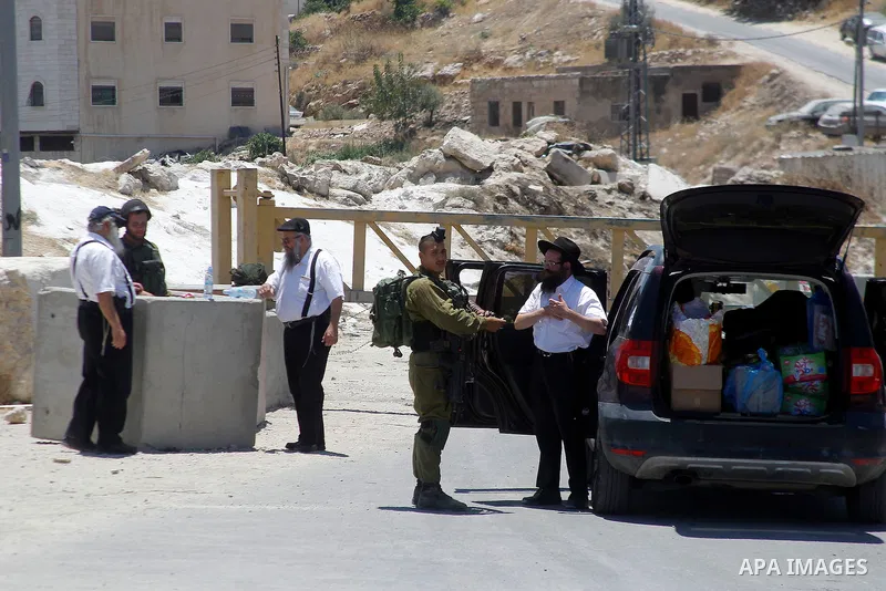 Israeli soldiers close a barrier blocking the road at a southern entrance of Hebron on July 3, 2016, as the army keeps the town under lockdown following clashes and attacks that killed two Israelis. Israeli troops locked...