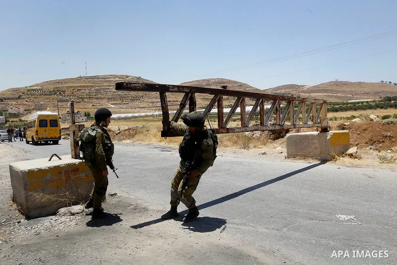 Israeli soldiers close a barrier blocking the road at the West Bank Al-Fawwar refugee camp, south of Hebron on July 3, 2016, as the army keeps the town under lockdown following clashes and attacks that killed two Israeli...