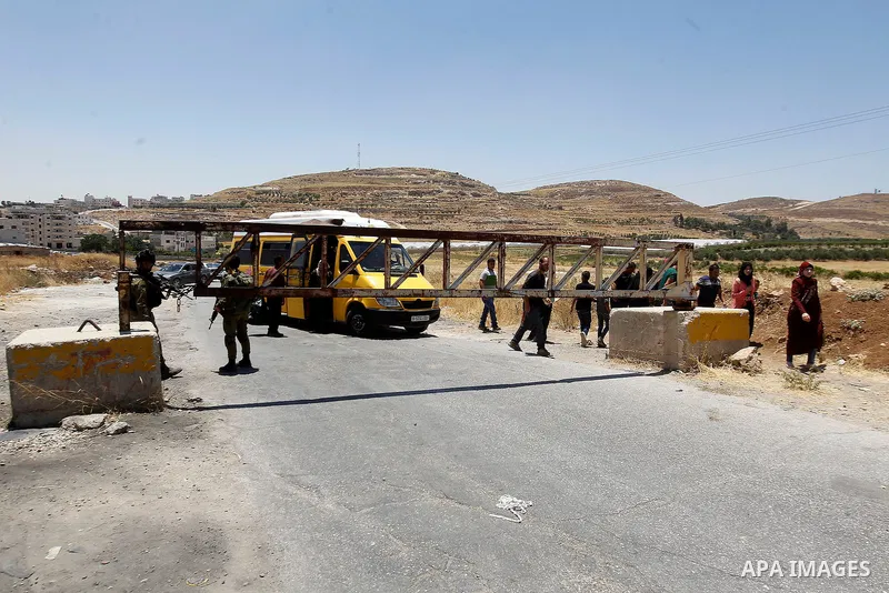 Israeli soldiers close a barrier blocking the road at the West Bank Al-Fawwar refugee camp, south of Hebron on July 3, 2016, as the army keeps the town under lockdown following clashes and attacks that killed two Israeli...
