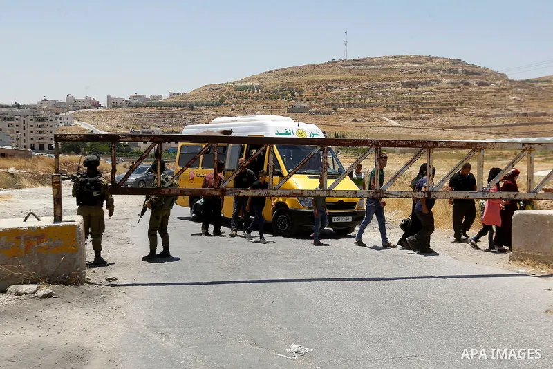 Israeli soldiers close a barrier blocking the road at the West Bank Al-Fawwar refugee camp, south of Hebron on July 3, 2016, as the army keeps the town under lockdown following clashes and attacks that killed two Israeli...