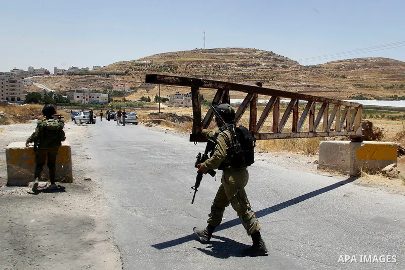 Israeli soldiers close a barrier blocking the road at the West Bank Al-Fawwar refugee camp, south of Hebron on July 3, 2016, as the army keeps the town under lockdown following clashes and attacks that killed two Israeli...
