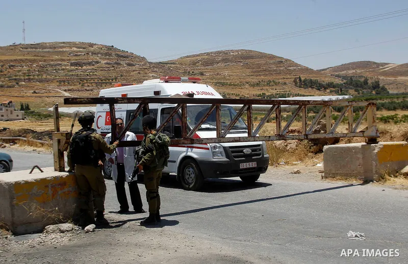 Palestinians wait to enter the ambulance from a barrier blocking the road at a southern entrance of Hebron on July 3, 2016, as the army keeps the town under lockdown following clashes and attacks that killed two Israelis...