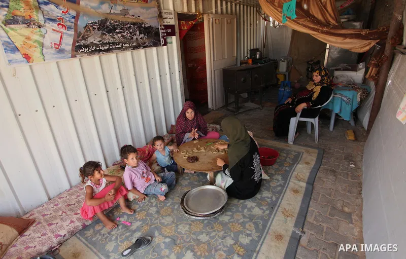 A Palestinian family, whose house was destroeyed during 2014 war, make traditional cakes inside their makeshift shelter, ahead of Eid-al-Fitr celebrations in Khan Younis in the southern Gaza Strip July 3, 2016. Photo by...