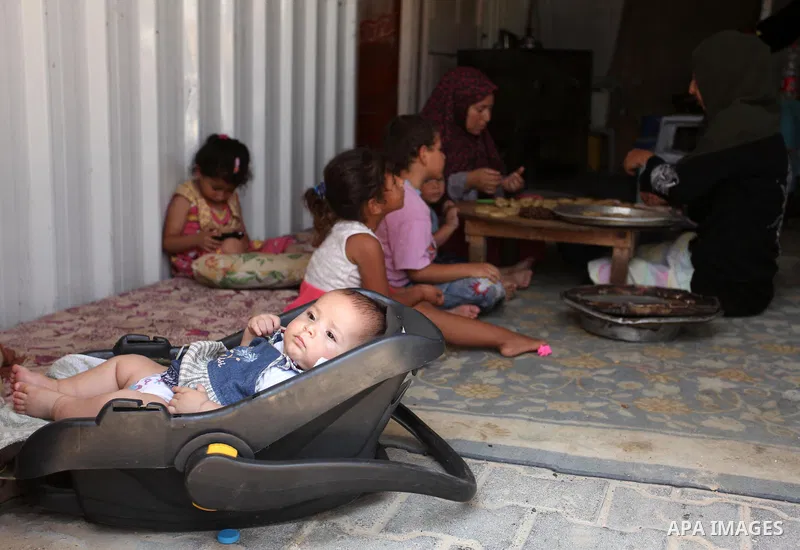 A Palestinian family, whose house was destroeyed during 2014 war, make traditional cakes inside their makeshift shelter, ahead of Eid-al-Fitr celebrations in Khan Younis in the southern Gaza Strip July 3, 2016. Photo by...