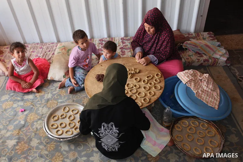 A Palestinian family, whose house was destroeyed during 2014 war, make traditional cakes inside their makeshift shelter, ahead of Eid-al-Fitr celebrations in Khan Younis in the southern Gaza Strip July 3, 2016. Photo by...