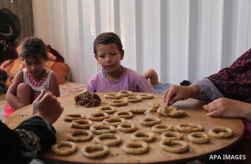 A Palestinian family, whose house was destroeyed during 2014 war, make traditional cakes inside their makeshift shelter, ahead of Eid-al-Fitr celebrations in Khan Younis in the southern Gaza Strip July 3, 2016. Photo by...