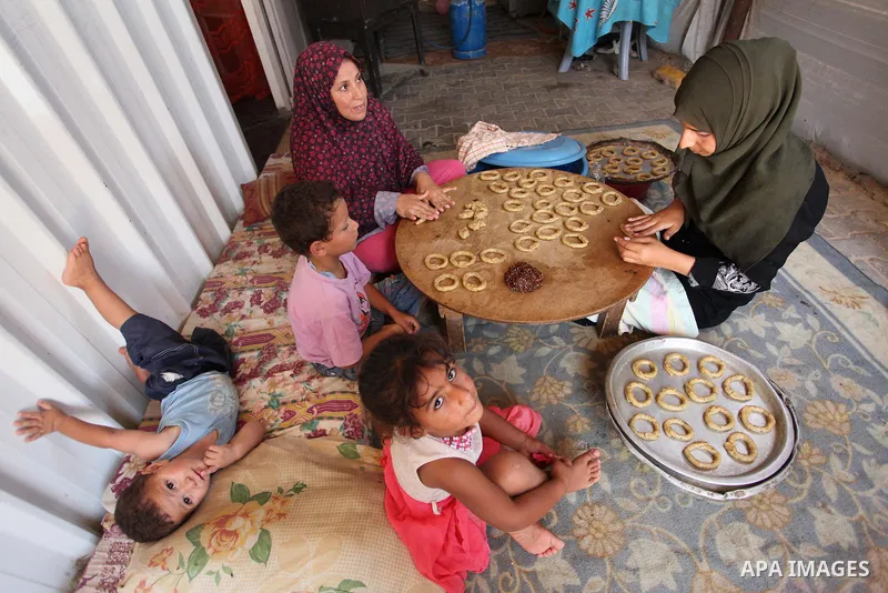 A Palestinian family, whose house was destroeyed during 2014 war, make traditional cakes inside their makeshift shelter, ahead of Eid-al-Fitr celebrations in Khan Younis in the southern Gaza Strip July 3, 2016. Photo by...