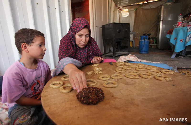 A Palestinian family, whose house was destroeyed during 2014 war, make traditional cakes inside their makeshift shelter, ahead of Eid-al-Fitr celebrations in Khan Younis in the southern Gaza Strip July 3, 2016. Photo by...