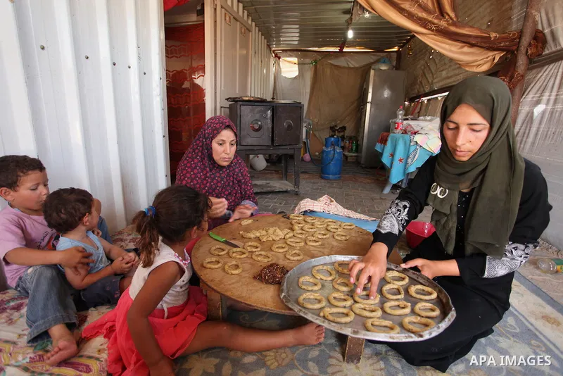 A Palestinian family, whose house was destroeyed during 2014 war, make traditional cakes inside their makeshift shelter, ahead of Eid-al-Fitr celebrations in Khan Younis in the southern Gaza Strip July 3, 2016. Photo by...