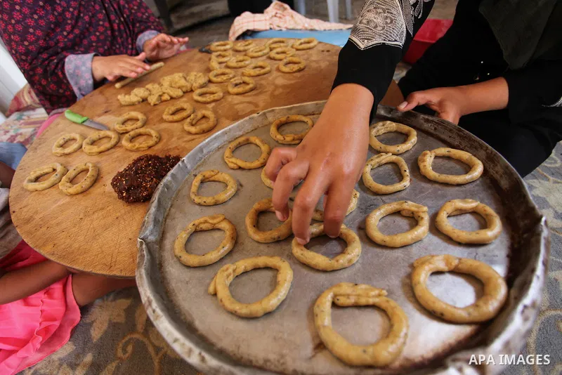 A Palestinian family, whose house was destroeyed during 2014 war, make traditional cakes inside their makeshift shelter, ahead of Eid-al-Fitr celebrations in Khan Younis in the southern Gaza Strip July 3, 2016. Photo by...