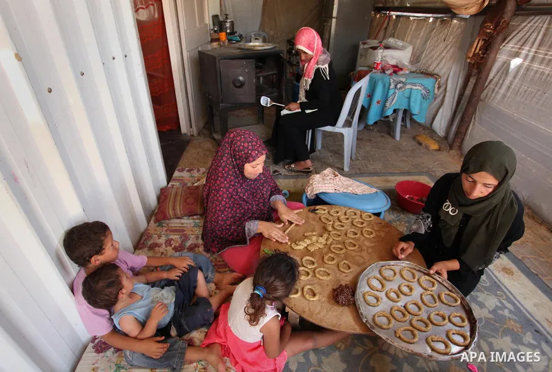A Palestinian family, whose house was destroeyed during 2014 war, make traditional cakes inside their makeshift shelter, ahead of Eid-al-Fitr celebrations in Khan Younis in the southern Gaza Strip July 3, 2016. Photo by...
