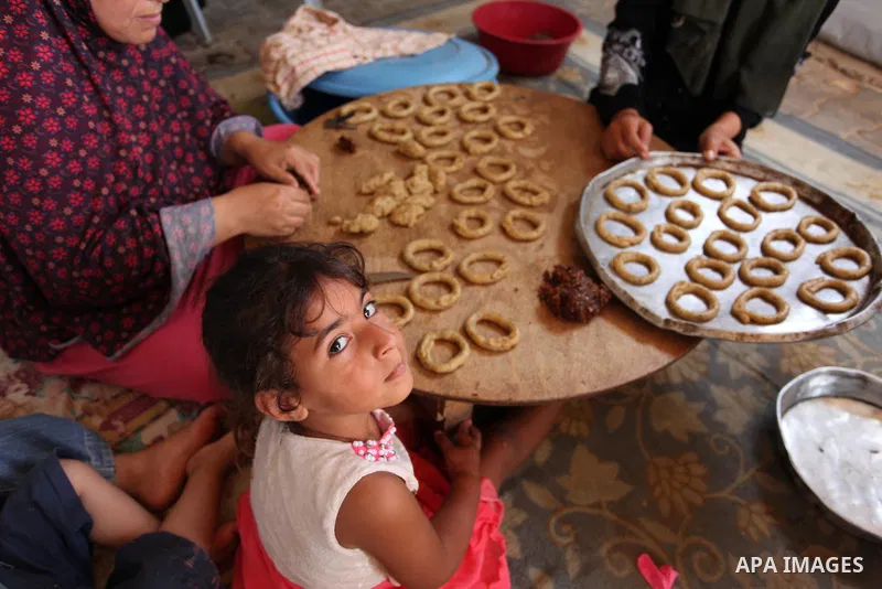 A Palestinian family, whose house was destroeyed during 2014 war, make traditional cakes inside their makeshift shelter, ahead of Eid-al-Fitr celebrations in Khan Younis in the southern Gaza Strip July 3, 2016. Photo by...