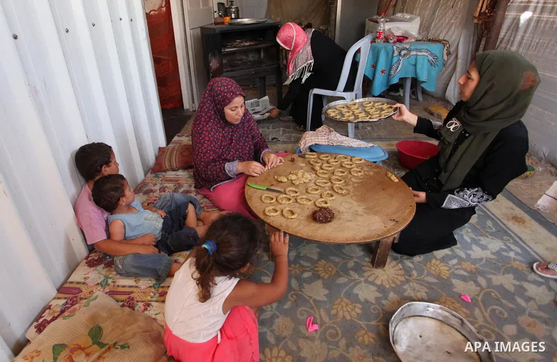 A Palestinian family, whose house was destroeyed during 2014 war, make traditional cakes inside their makeshift shelter, ahead of Eid-al-Fitr celebrations in Khan Younis in the southern Gaza Strip July 3, 2016. Photo by...